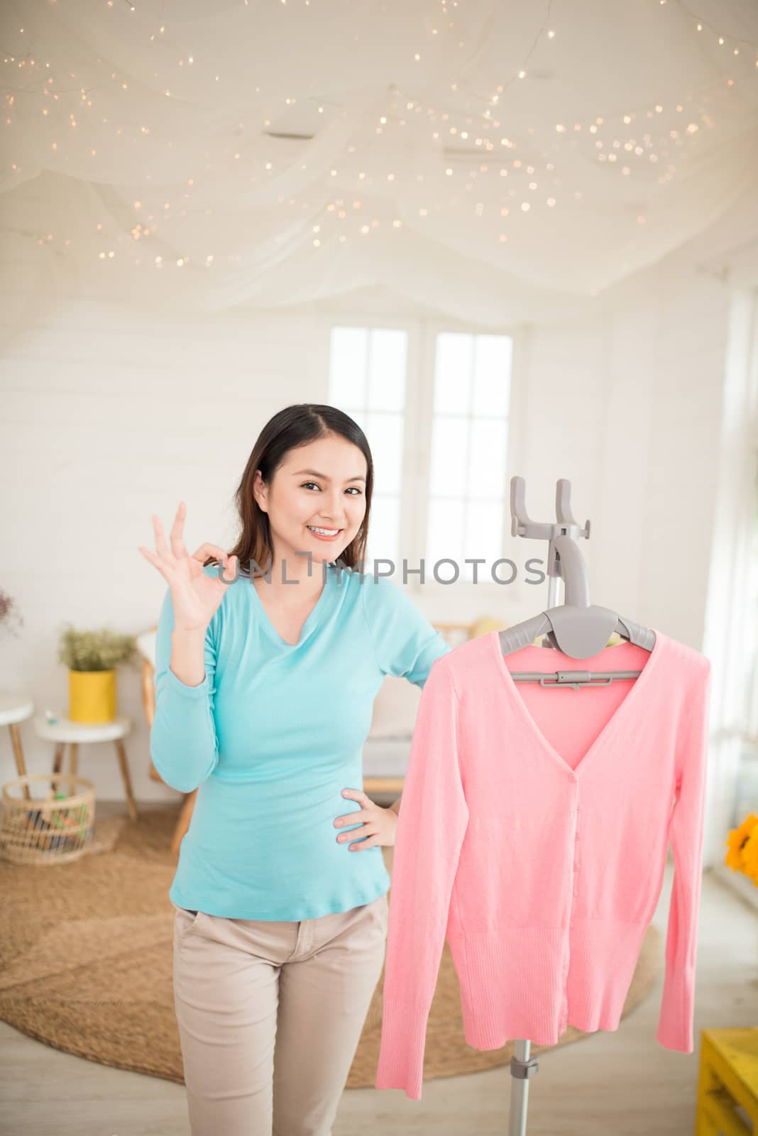 Happy young asian woman finish steaming clothes in room by makidotvn