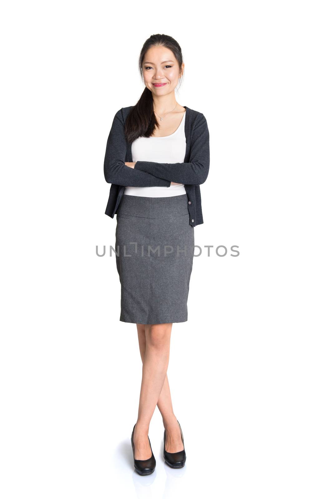 Full length portrait of young Asian female arms crossed and smiling, standing isolated on white background.
