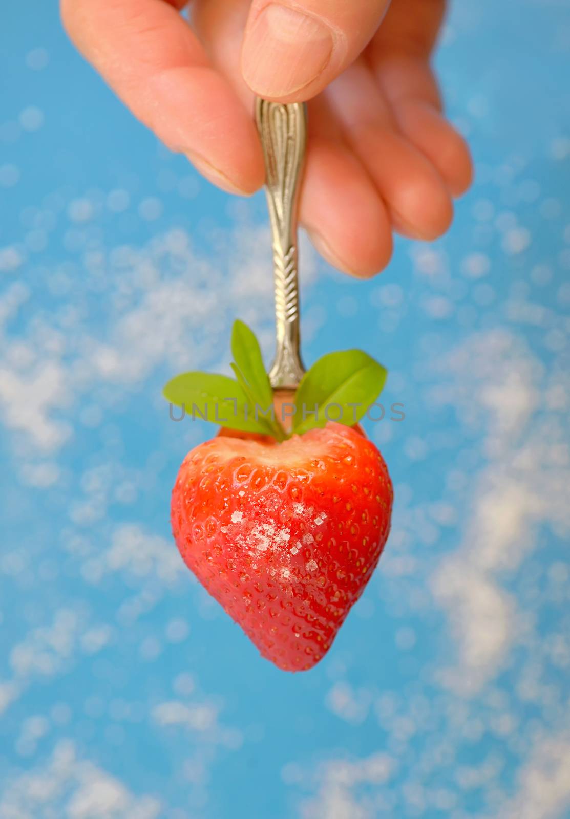 A heart shaped strawberry in spoon and sugar on background