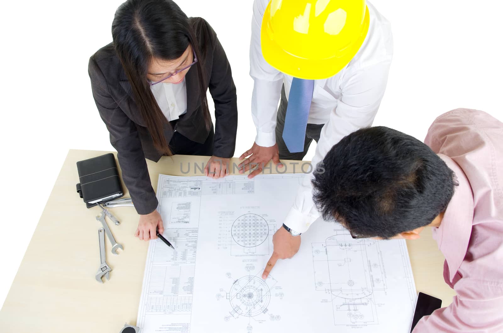 Above view of three architects standing in front of the table and discussing design project.