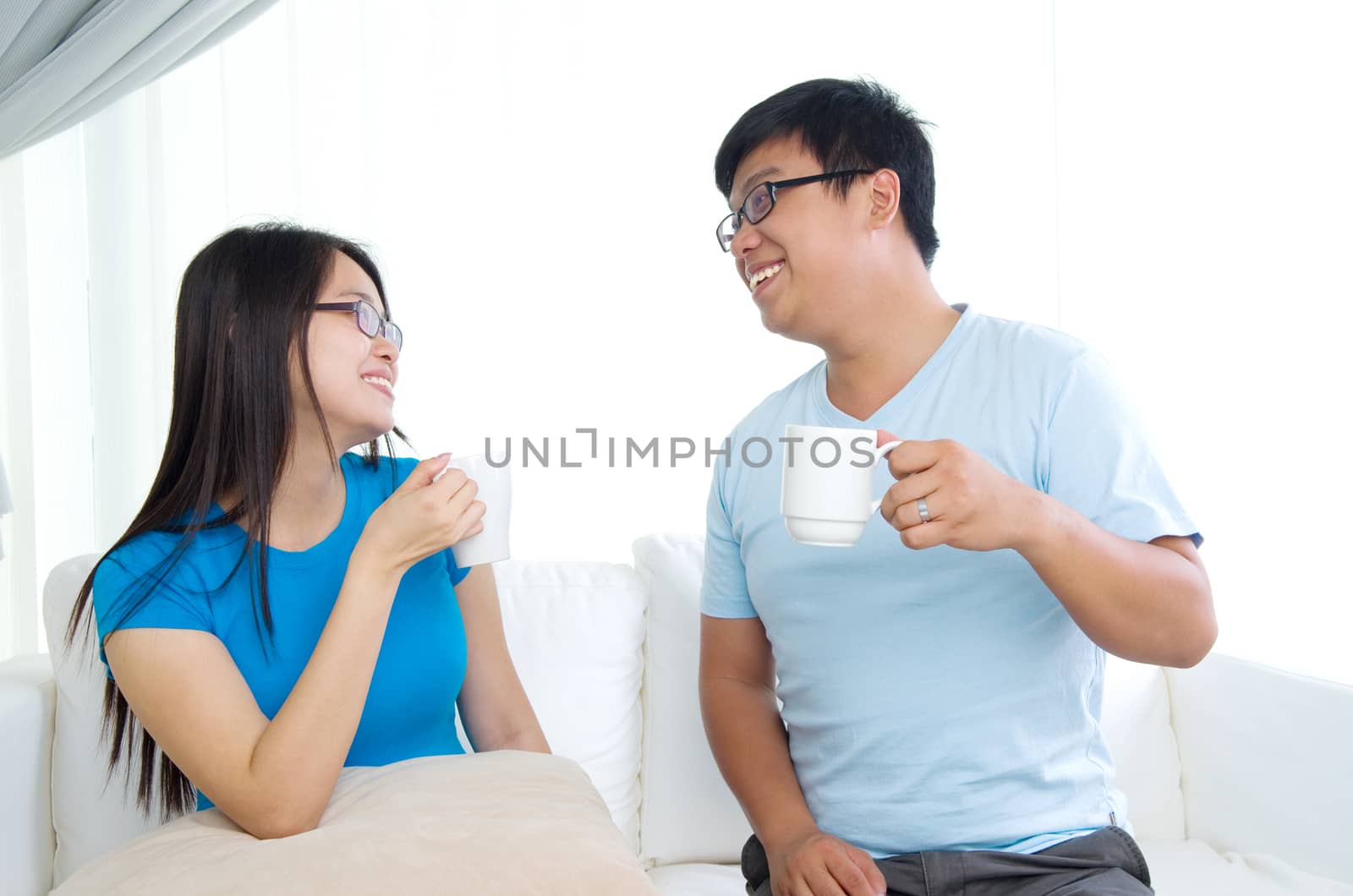 sweet young couple sitting in sofa, looking at each other.