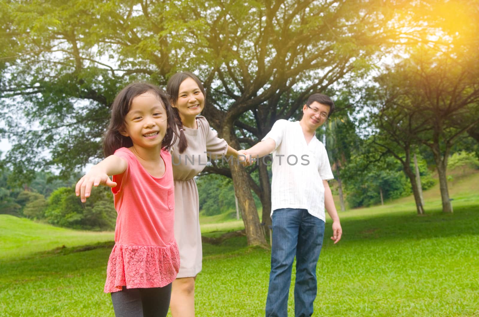 Portrait of joyful happy Asian family playing together at outdoor park during summer sunset.