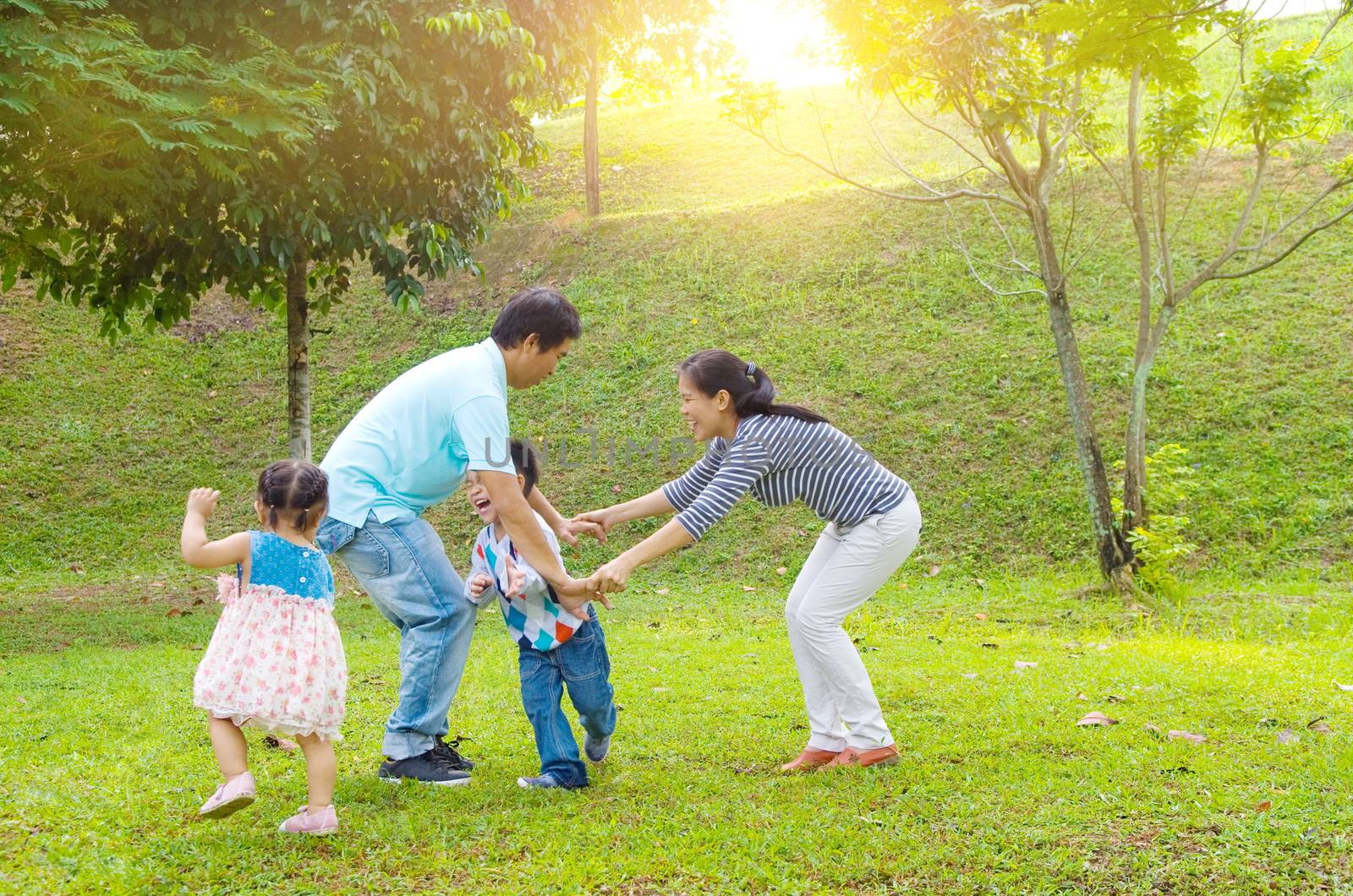 Asian family outdoor quality time enjoyment, asian people playing during beautiful sunset.