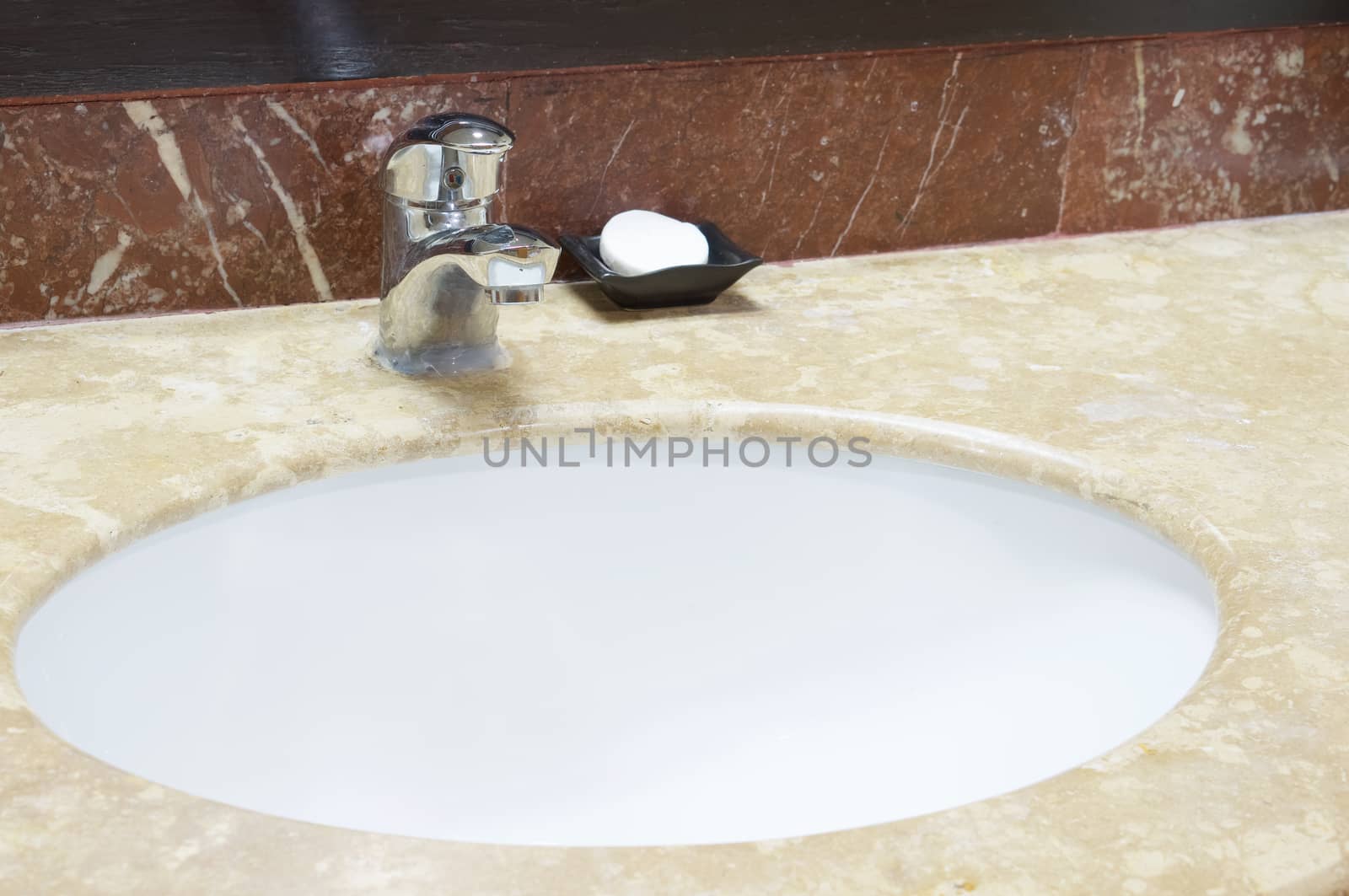 Chromium faucet and white soap with white wash basin and marble.