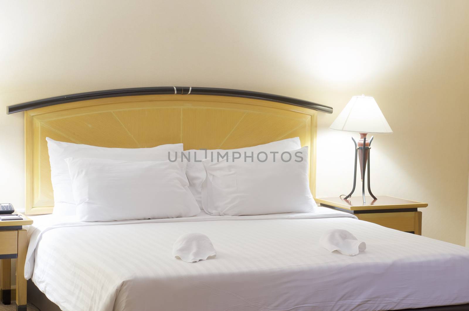 Big pillow on white and clean bed with lamp in bedroom at hotel.