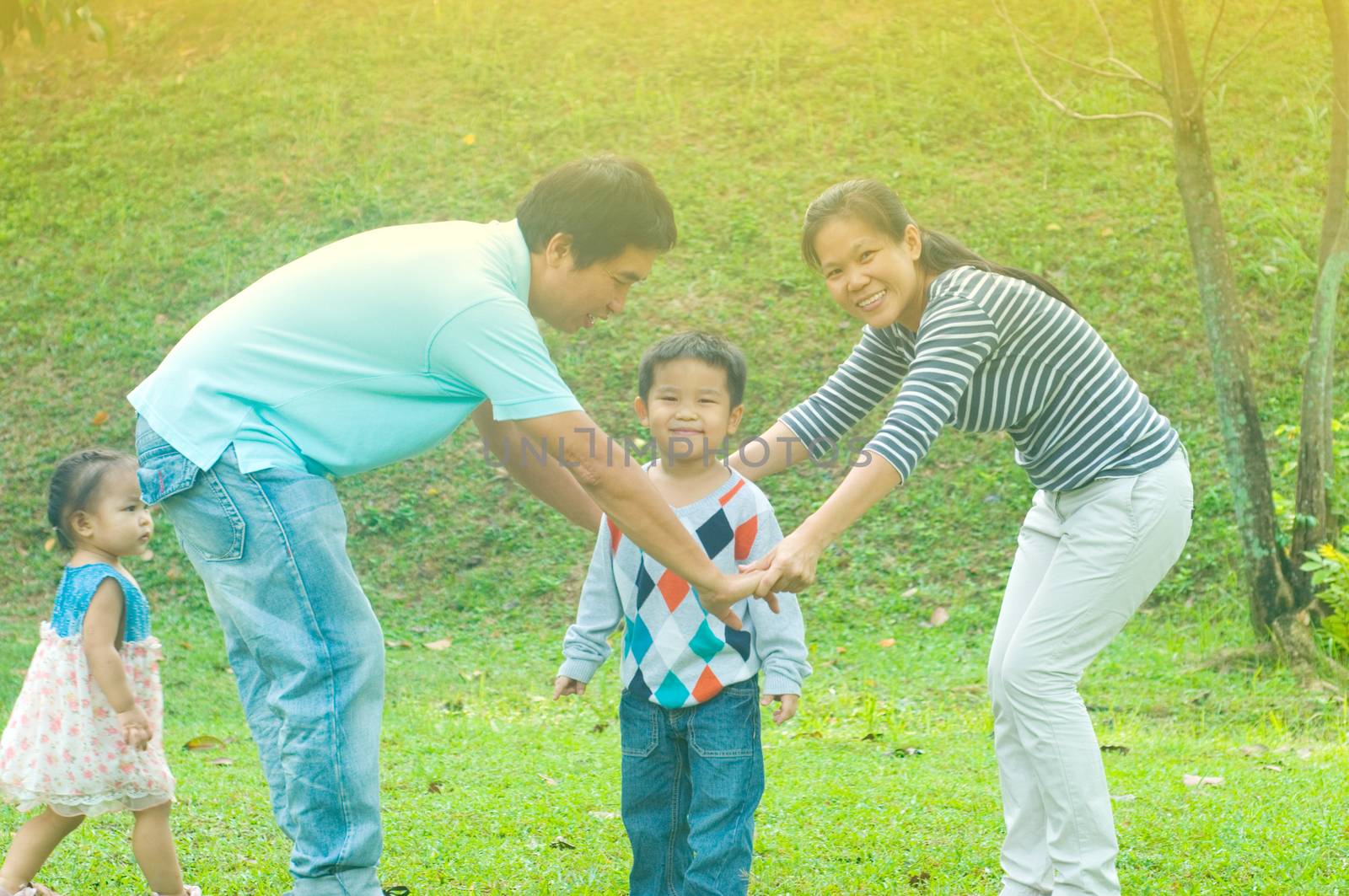 Asian family outdoor quality time enjoyment, asian people playing during beautiful sunset.