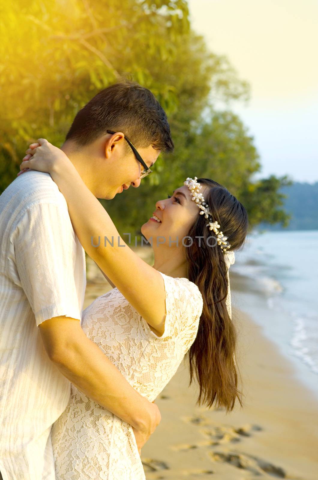Outdoor Bride and groom on the beach with sunset in the evening.