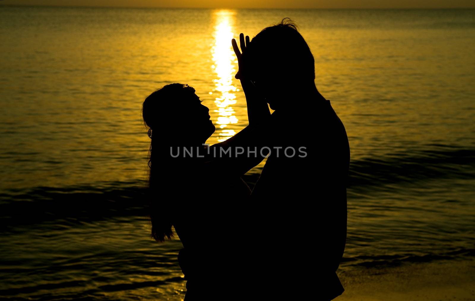 silhouette of a young bride and groom in beach on Sunset background