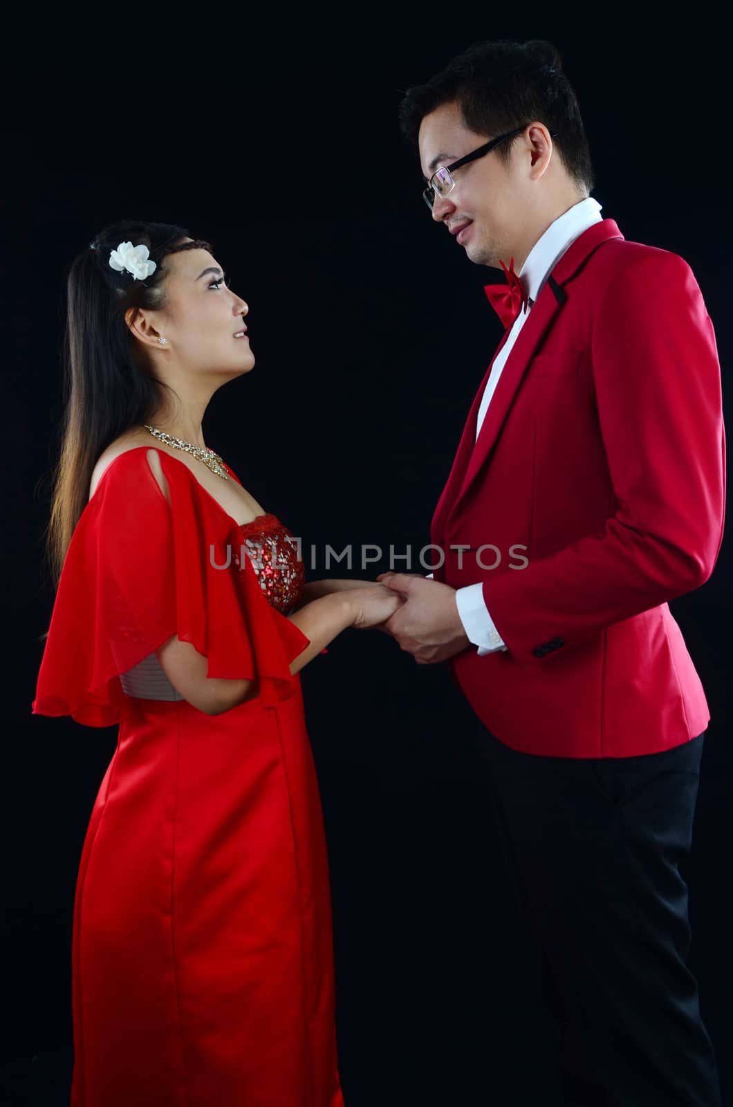 Portrait of young elegant enamoured just married groom and bride embracing at Wedding on black background