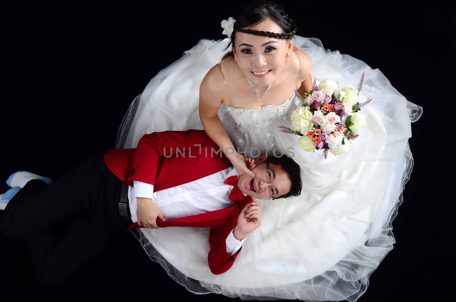 Portrait of young elegant enamoured just married groom and bride embracing at Wedding on black background