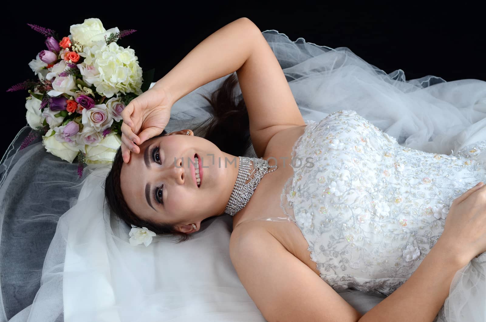 attractive asian woman wearing wedding dress isolated on black background