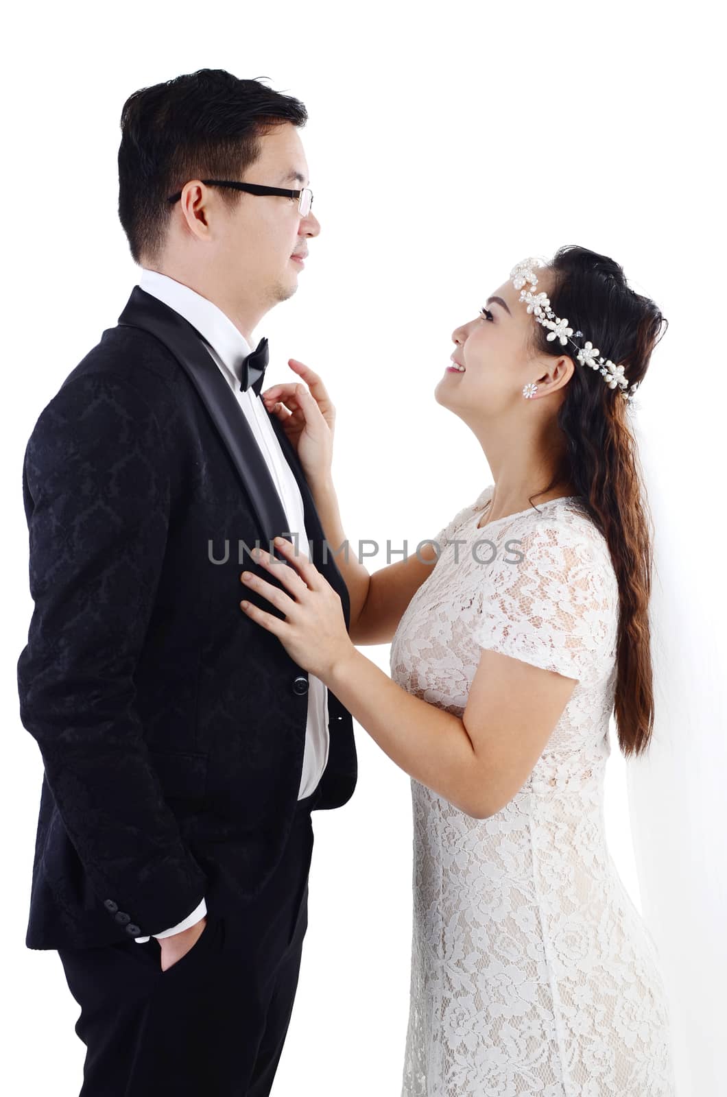 Portrait of young elegant enamoured just married groom and bride embracing at Wedding on white background