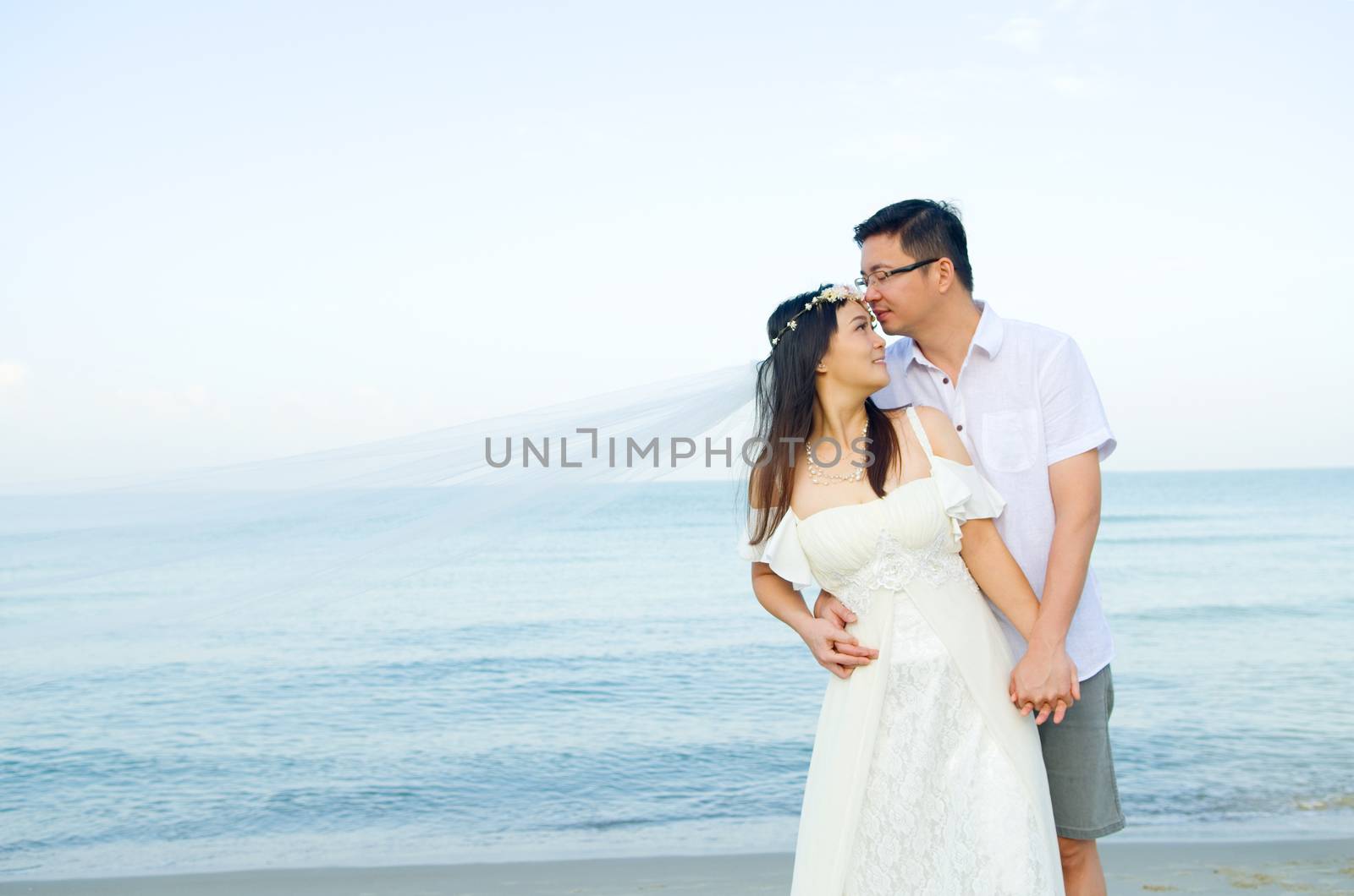 Asian bride and groom on a tropical beach. Wedding and honeymoon concept.