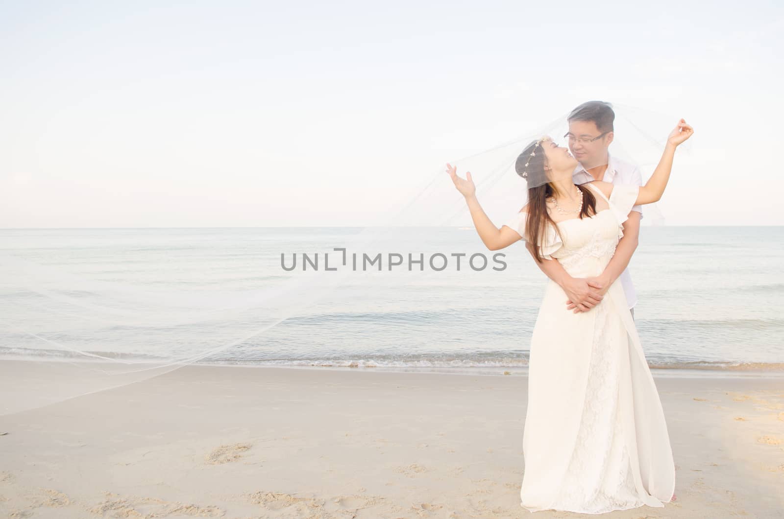 Asian bride and groom on a tropical beach. Wedding and honeymoon concept.