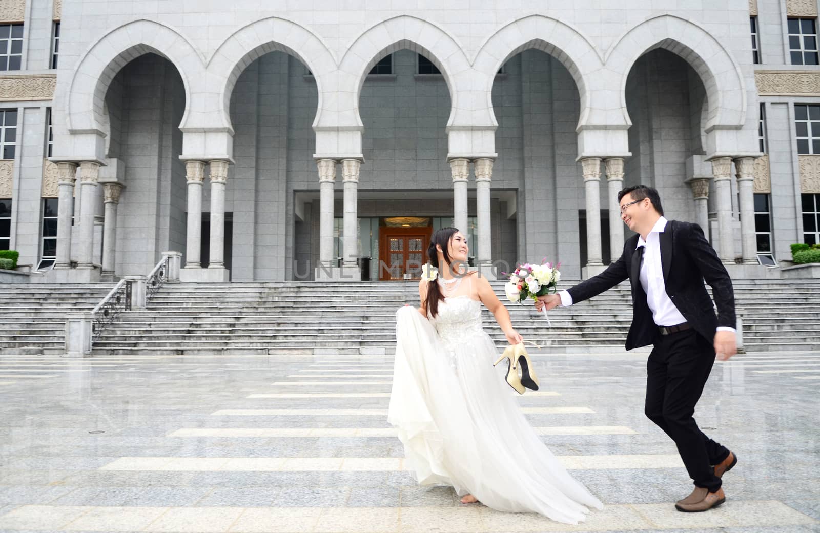 Happy bride and groom enjoying their wedding in the background of the building with beautiful architecture. Happy young wedding couple