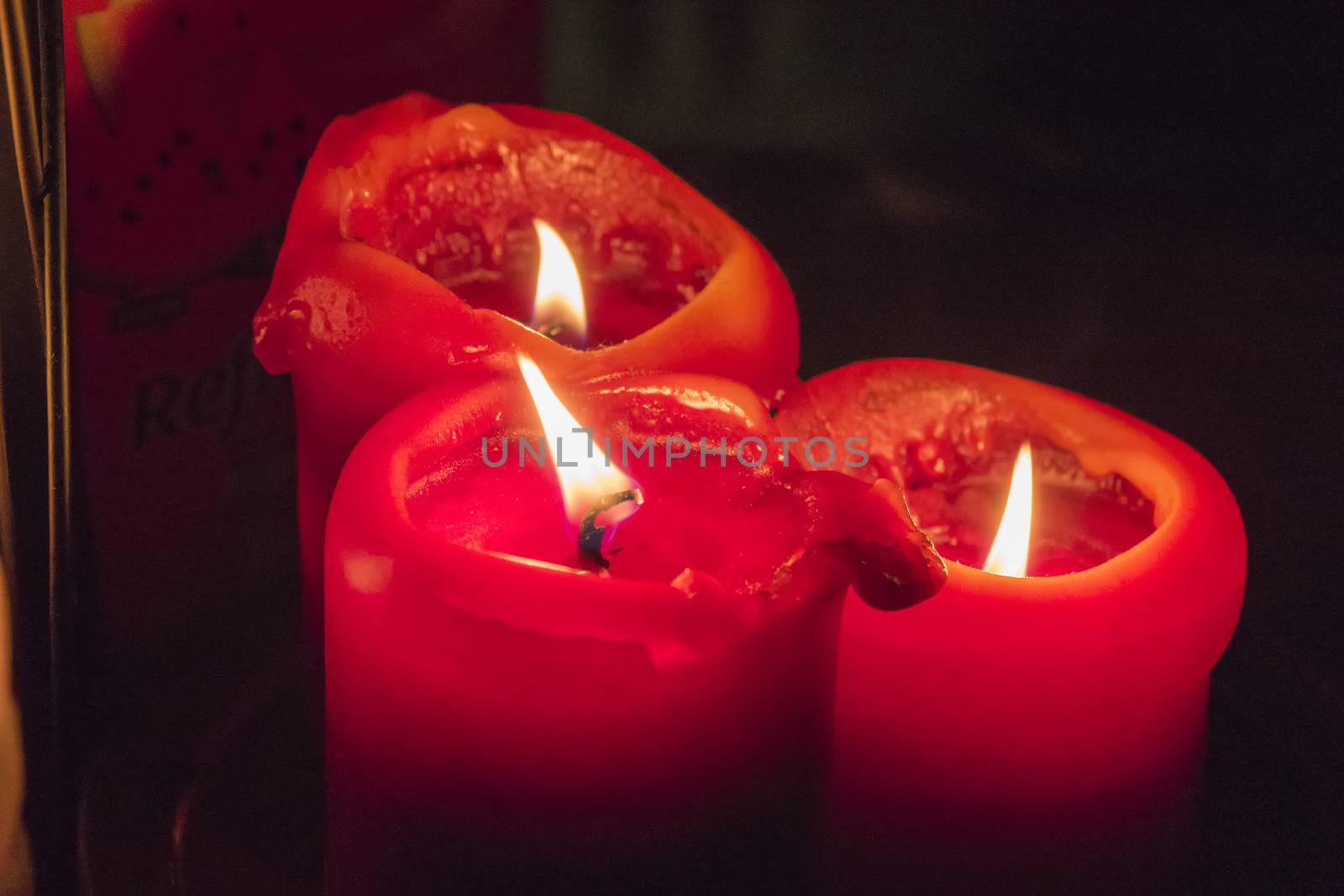 Three red candles burning in the dark by max8xam