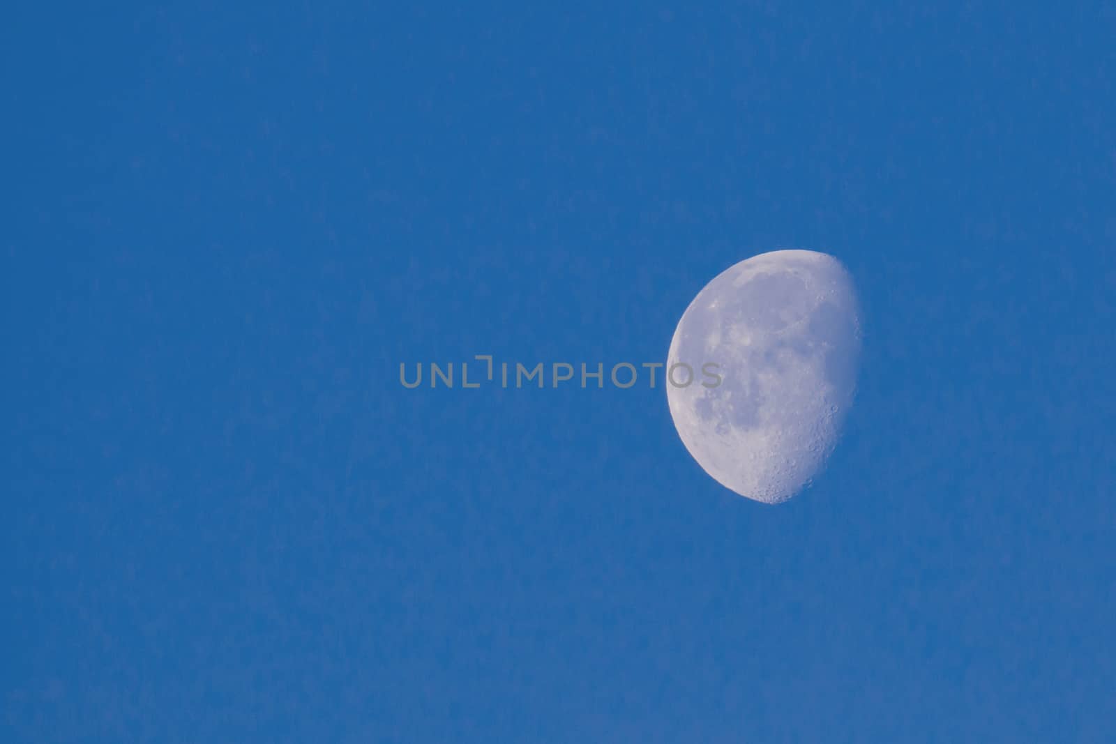 Waxing Gibbous Moon in blue sky showing craters, with copy space for text.