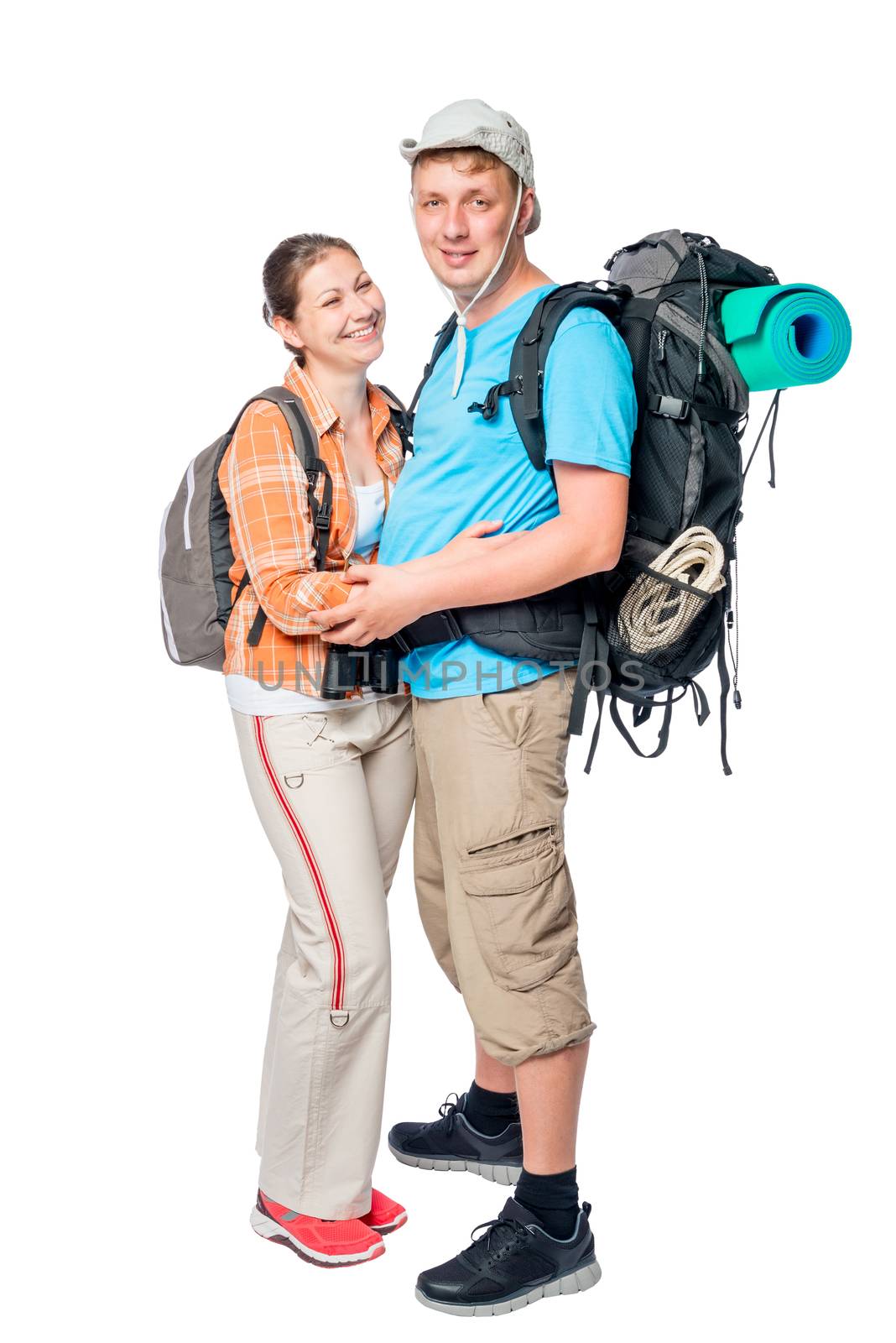 Hugging couple of young tourists with backpacks posing on white background
