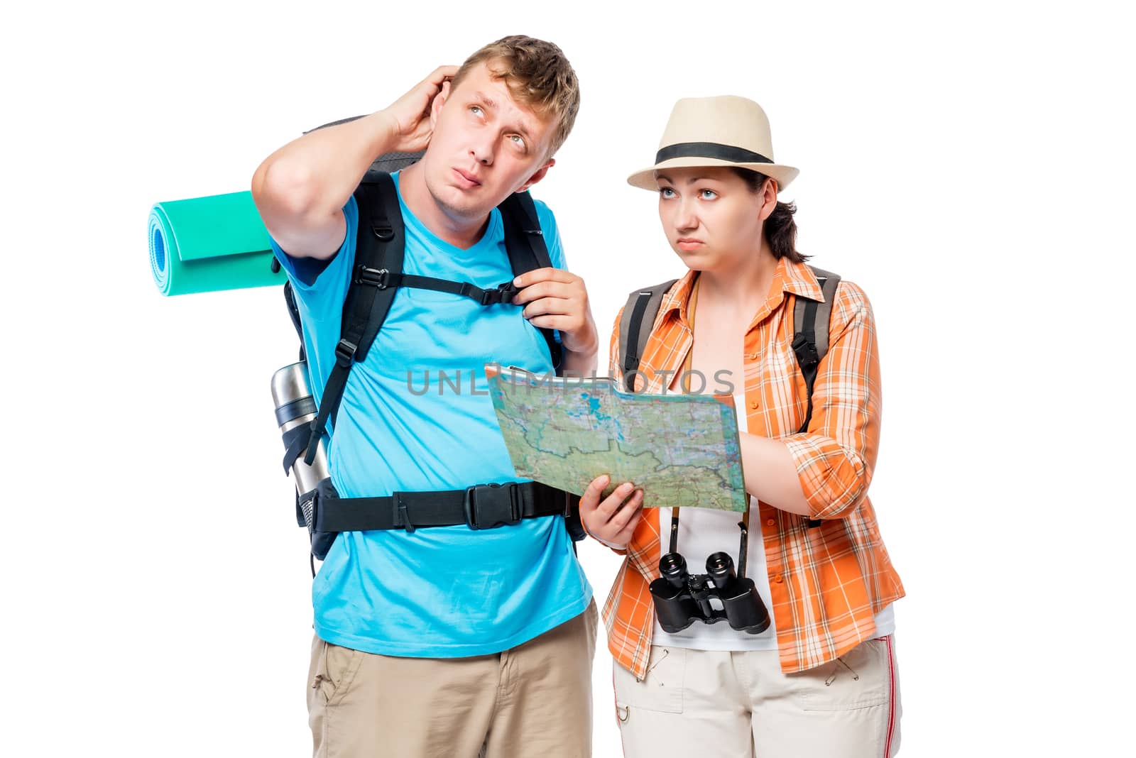 Lost stray couple of tourists with backpacks with a card pondering, posing against white background
