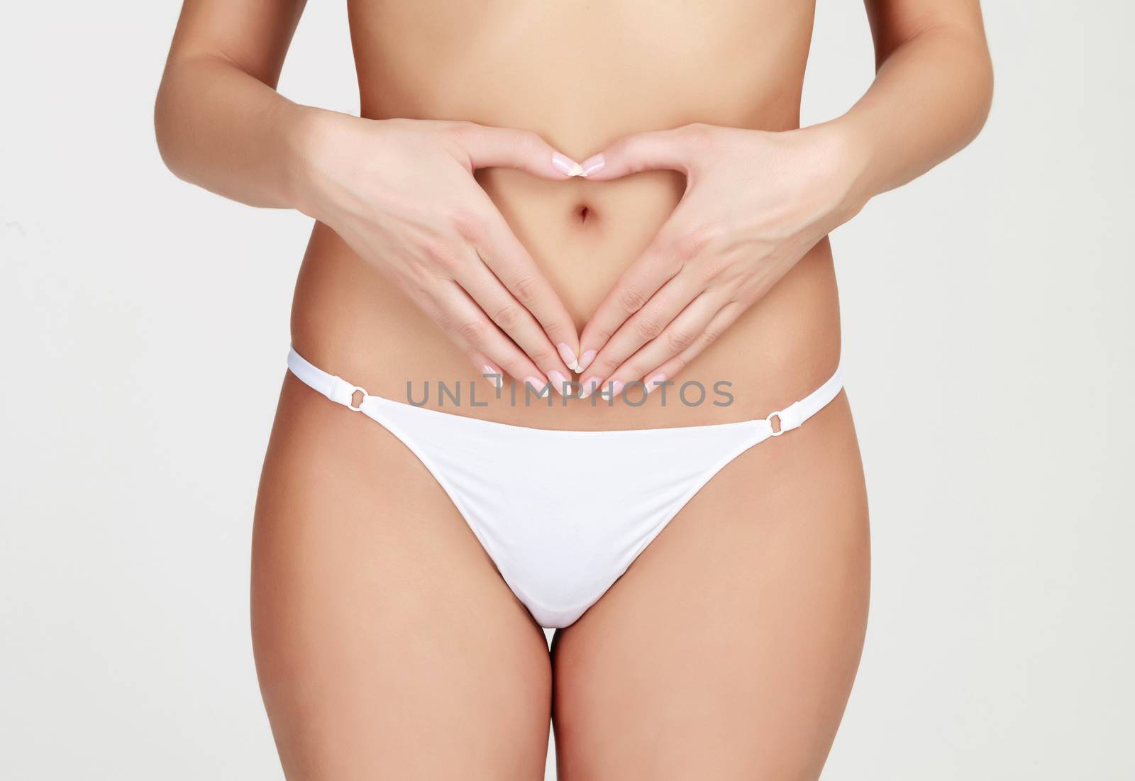 Woman's hands forming a heart symbol on the belly