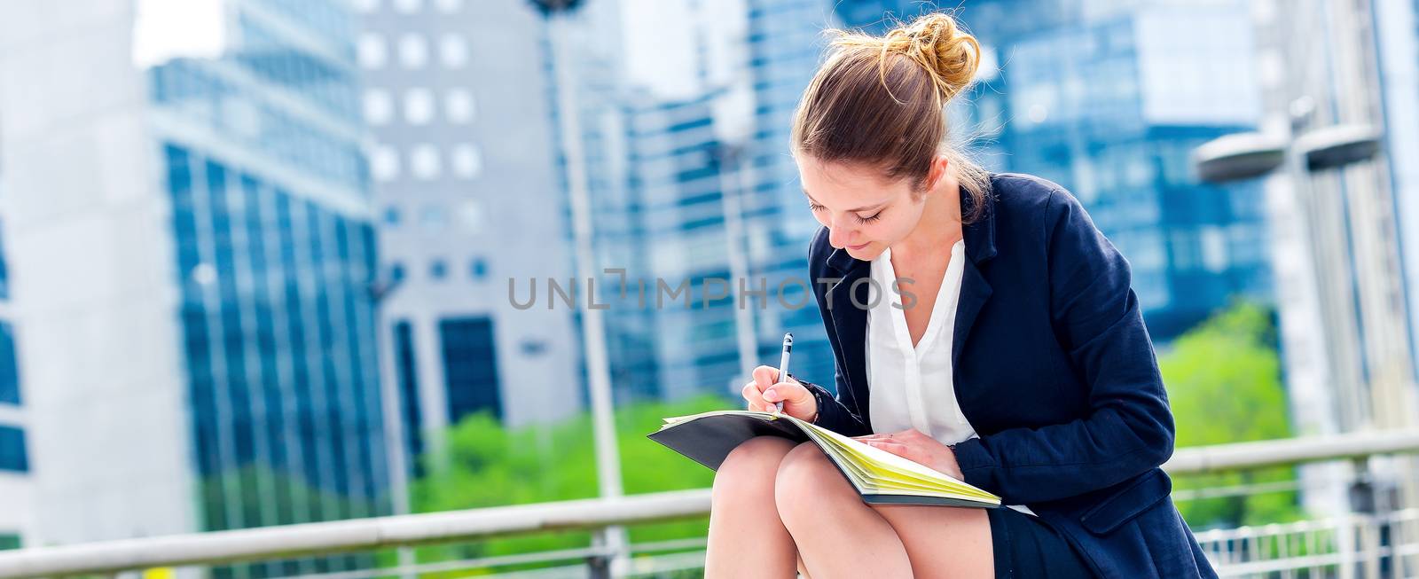 dynamic young executive girl taking notes on her agenda, outside. Symbolizing a job search or a trade of outsourcing