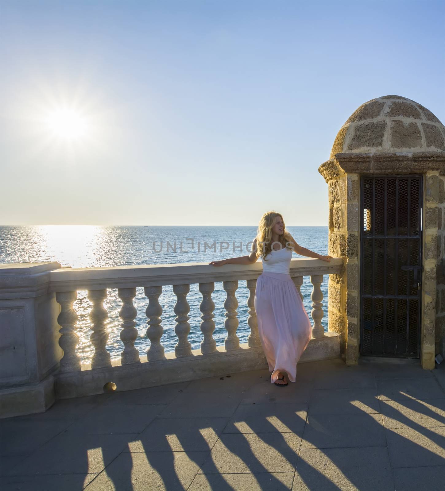 Young woman posing on a balcony facing the sea