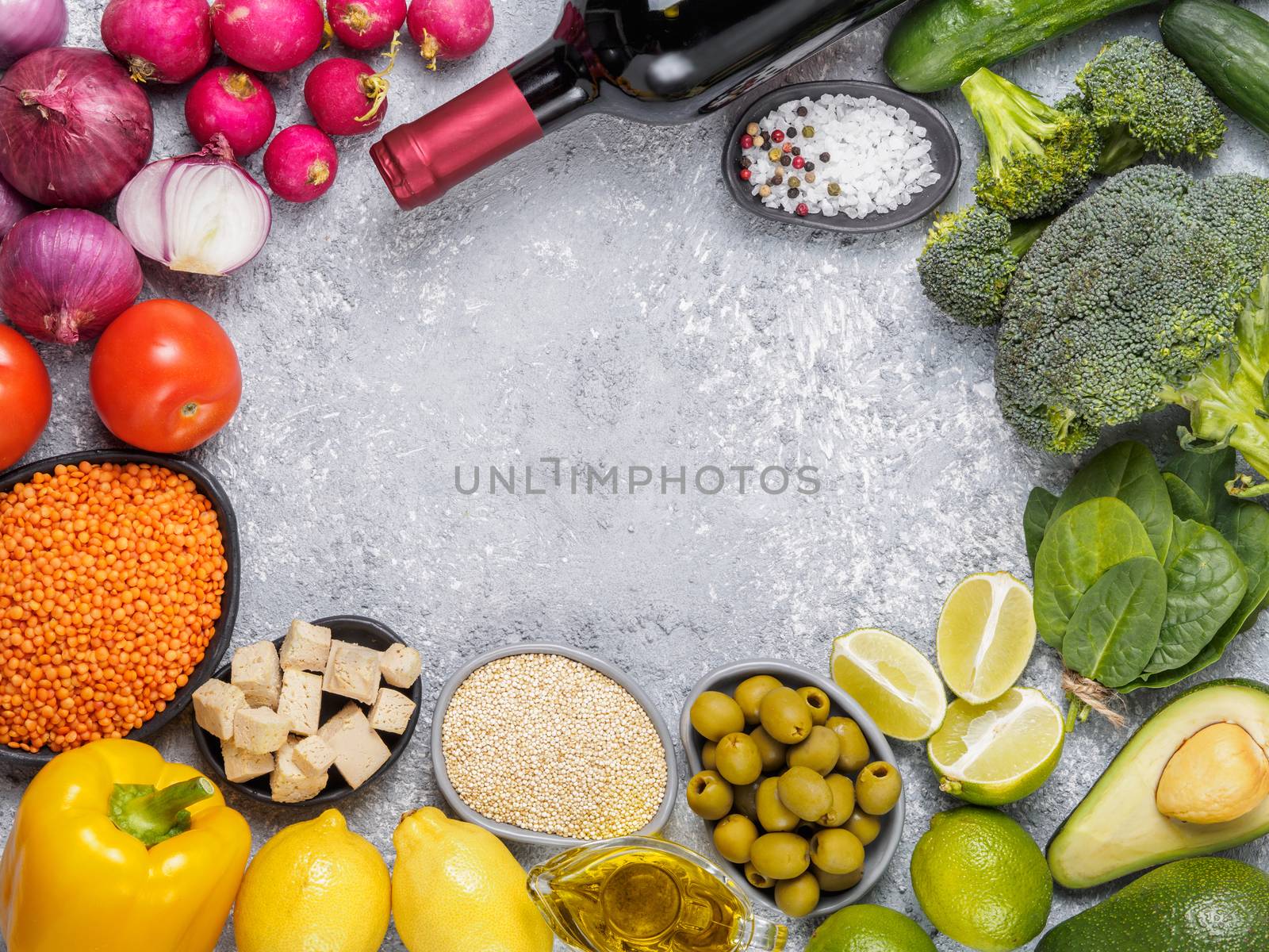 Colorful food background. Food ingredients with copy space. Cereals, vegetables and wine bottle on gray concrete background.