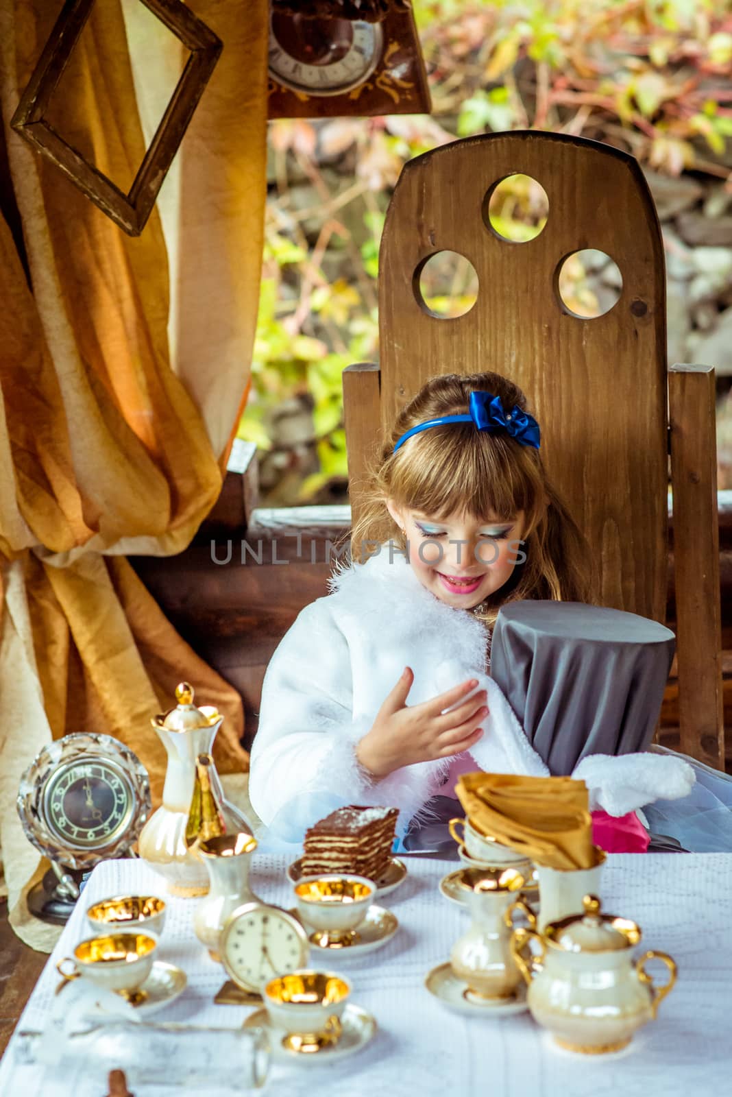 An little beautiful girl holding cylinder hat with ears like a rabbit in the hands at the table by okskukuruza