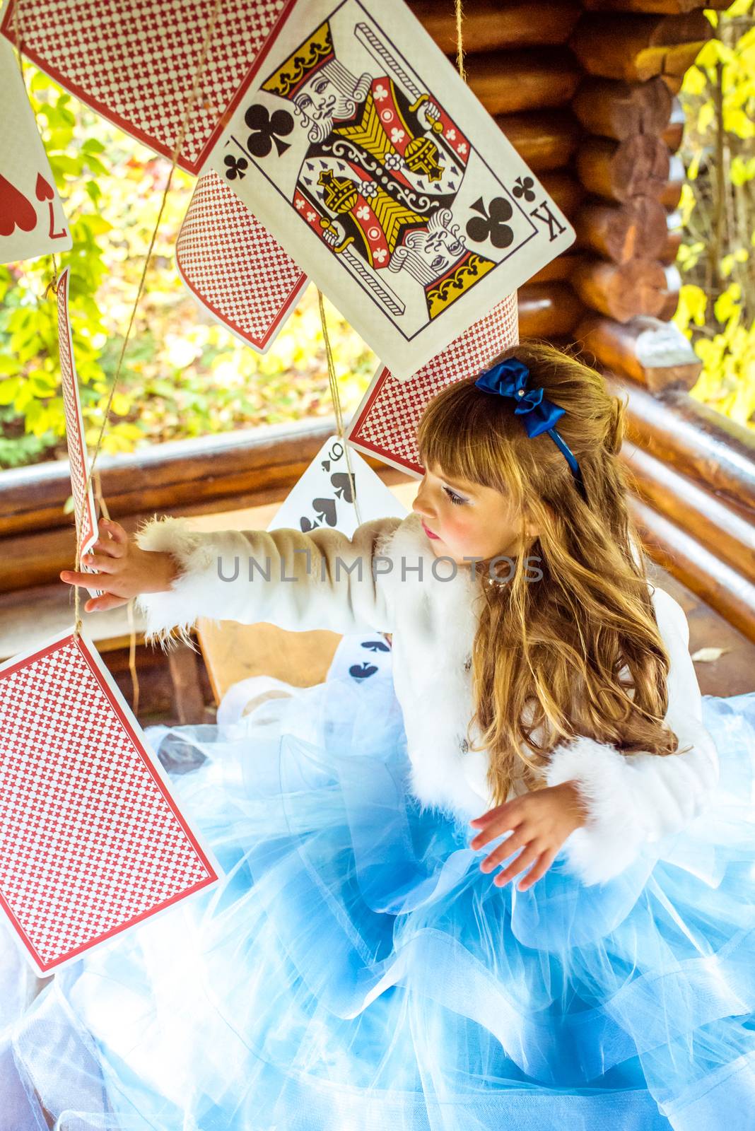 An little beautiful girl playing and dancing with large playing cards on the table by okskukuruza