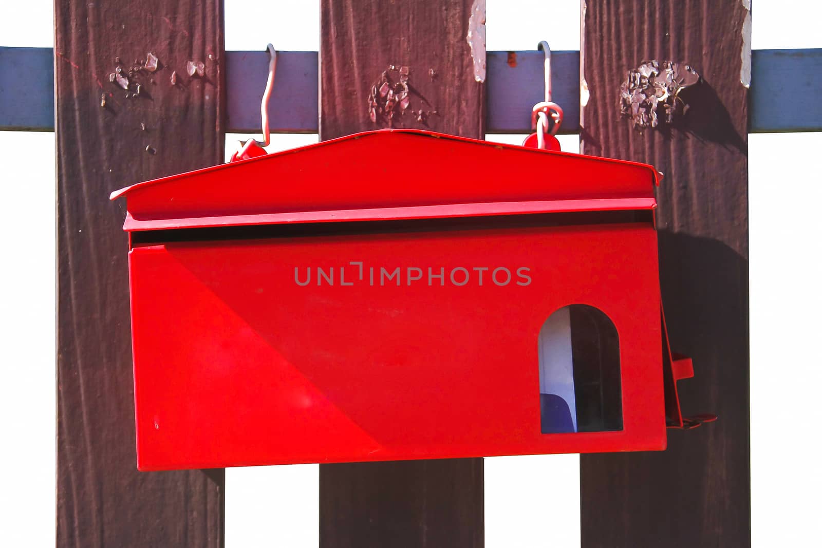 Red mailbox on brown gates