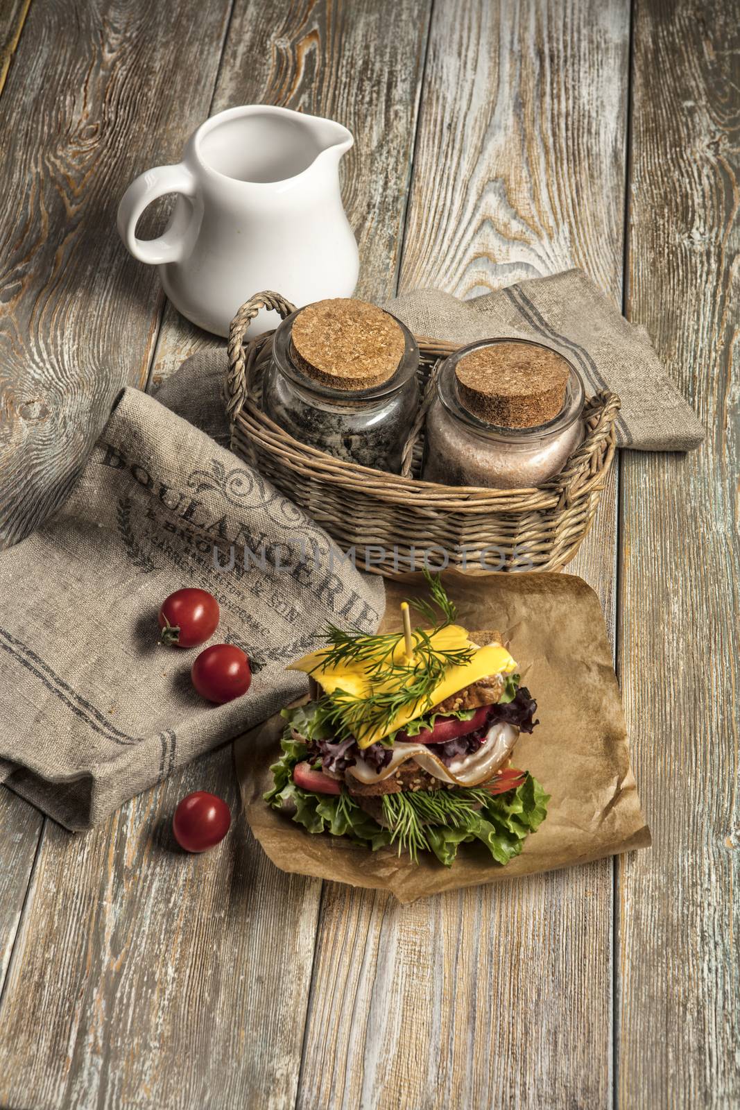 Sandwich with vegatables and tomatoes on an old wooden table