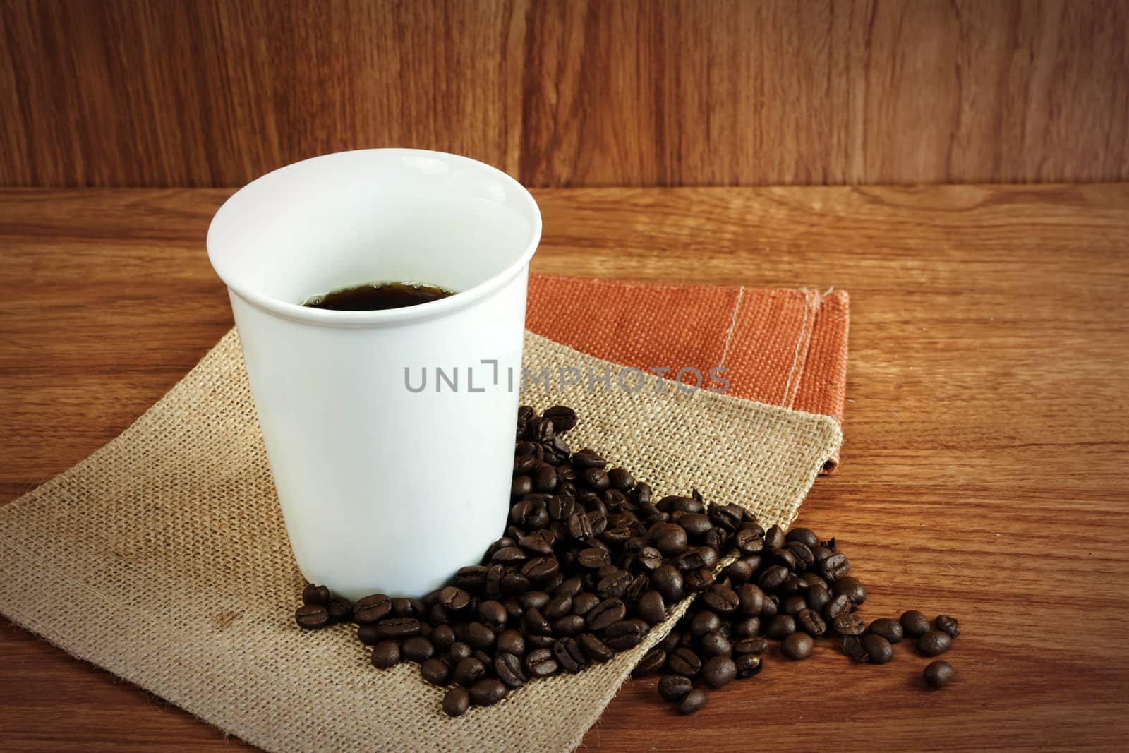 Black hot coffee in white cup and coffee bean on wood table