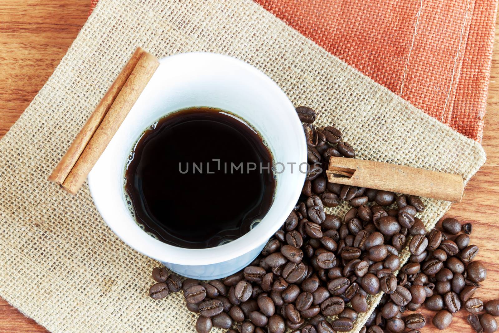 Black hot coffee cup with cinnamon and coffee bean on wood table