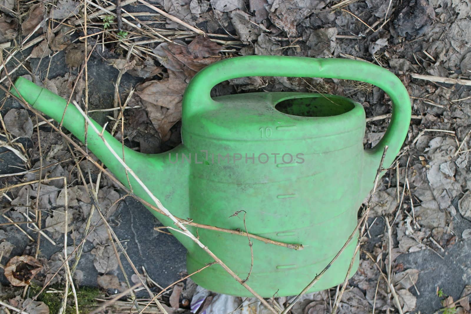 green plastic watering can an abandoned garden still life