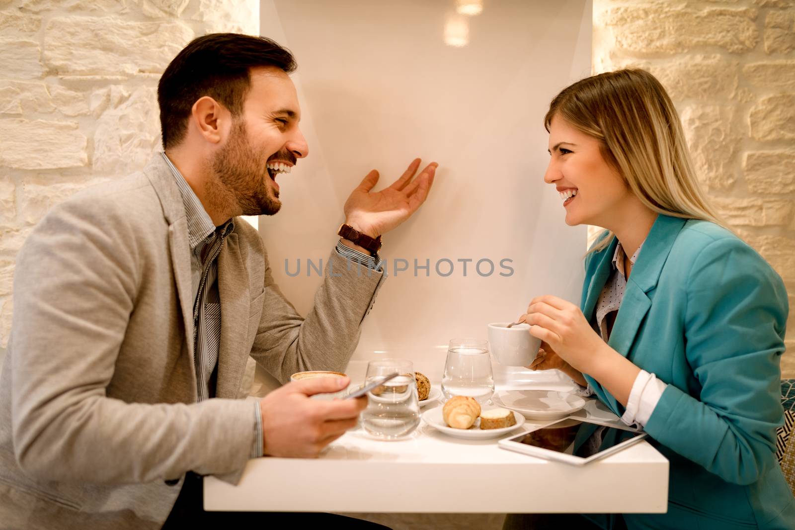 Young smiling businesspeople on a break in a cafe. They are drinking coffee and talking with smile.