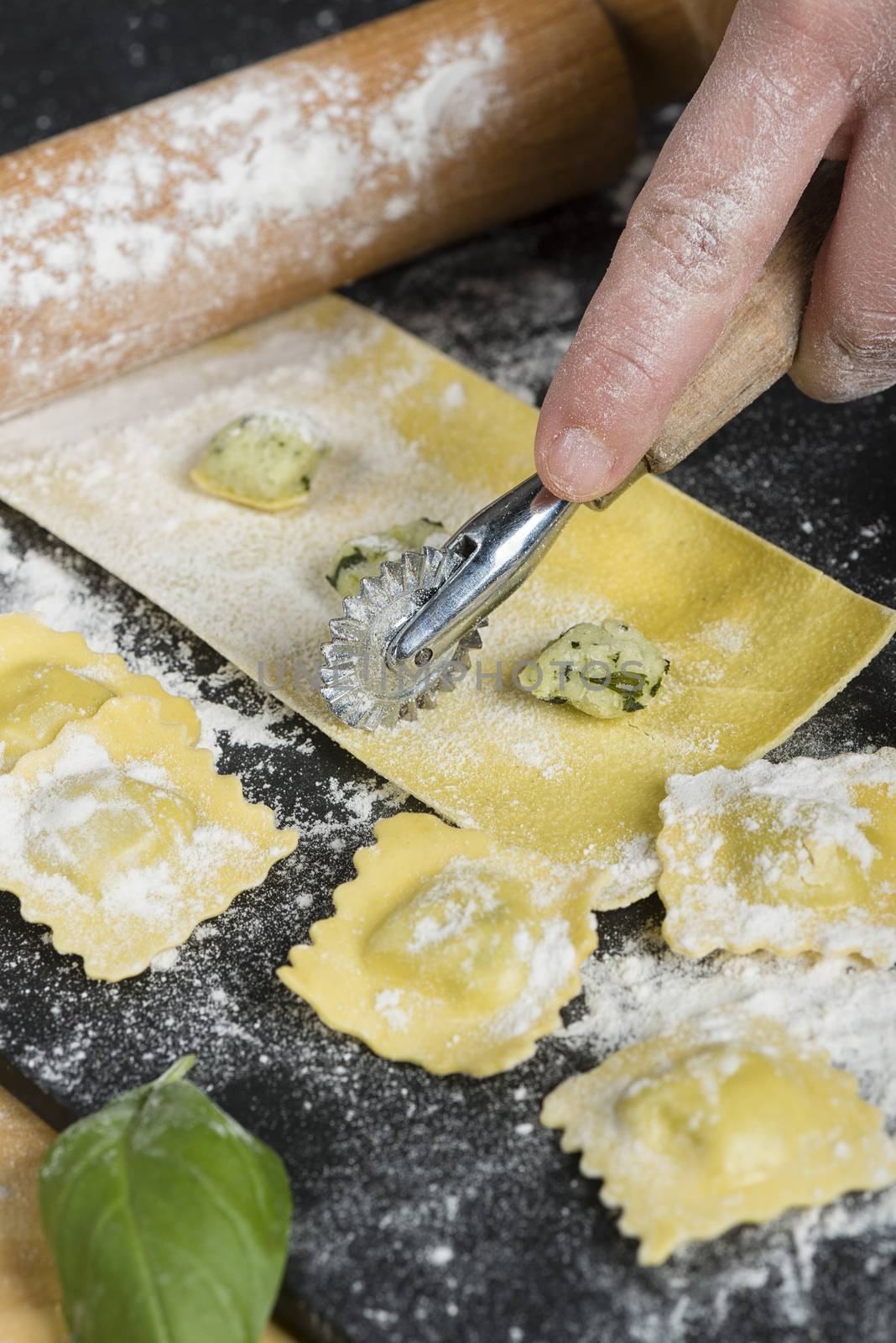 Preparing ravioli in the kitchen with tools and ingredients : dough, flour, eggs, stuffing, cutter, roller, board.