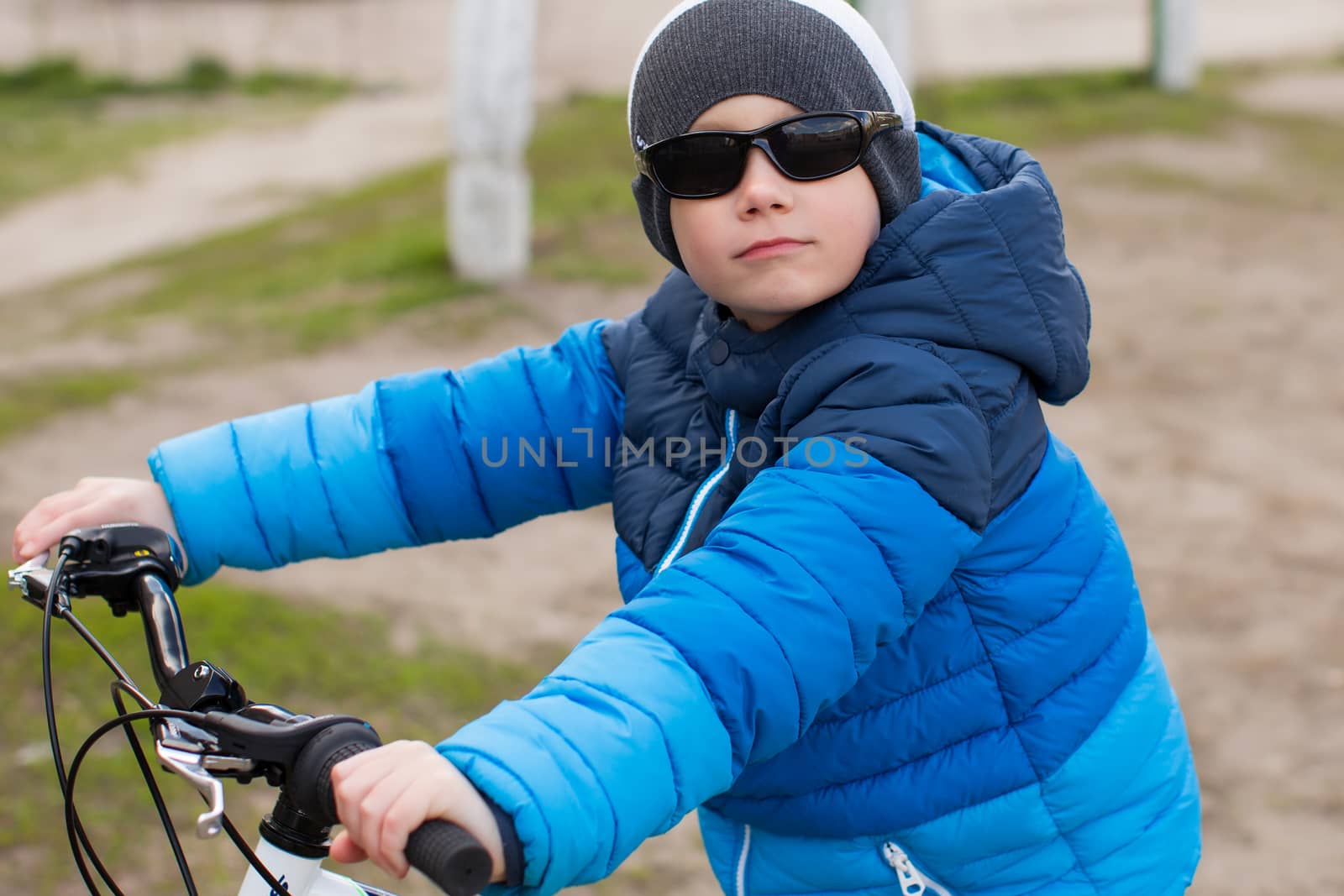 A boy wearing sunglasses sits on a bicycle. by lanser314