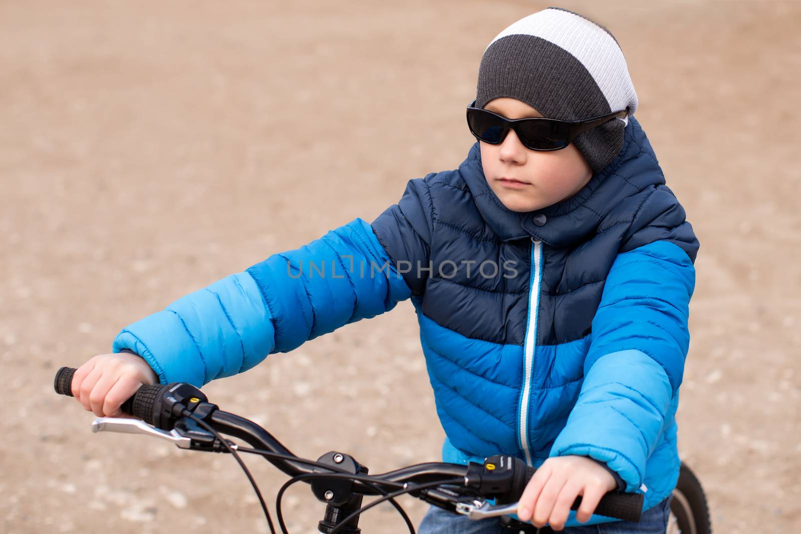 A boy wearing sunglasses sits on a bicycle. by lanser314
