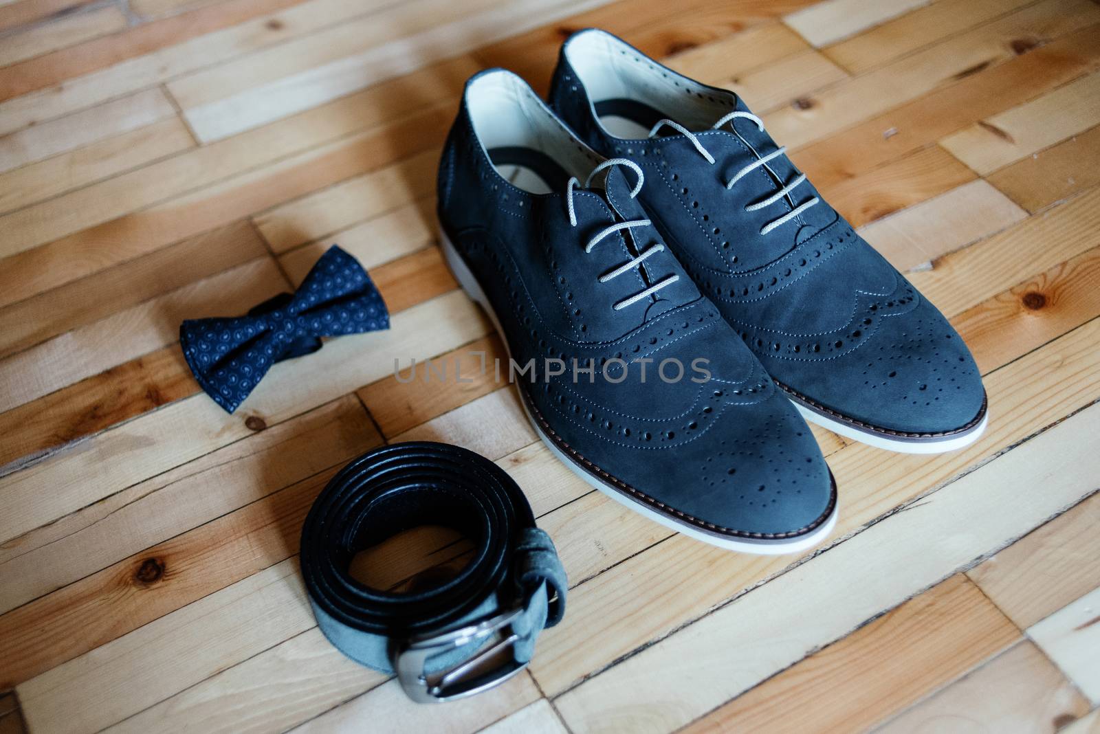 Wedding shoes, belt and bowtie on a wooden background. Wedding accessories for the groom. Groom clothes.