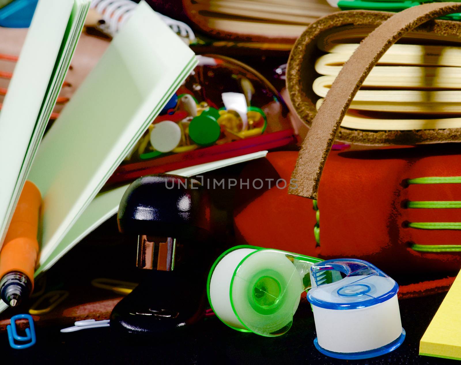 Background of Stationery Items with Notepads, Pens, Pencils, Paper Clips, Tape Dispenser, Marker and Stapler closeup