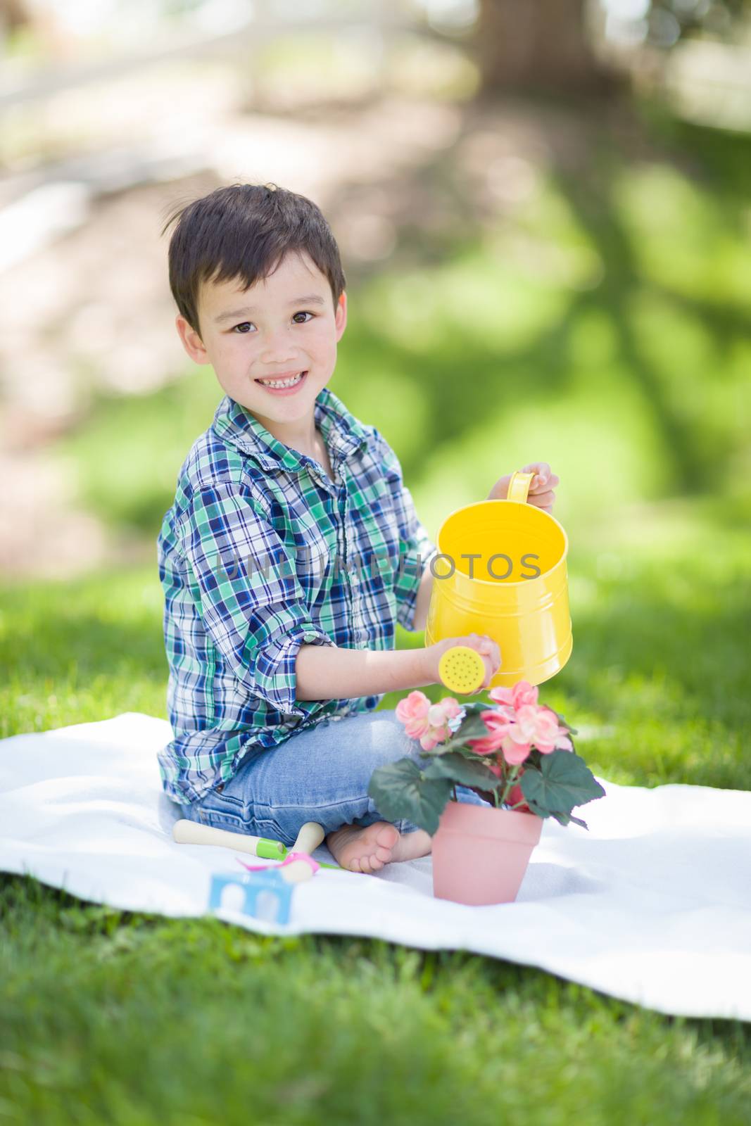 Mixed Race Young Boy Watering His Potted Flowers Outside On The  by Feverpitched
