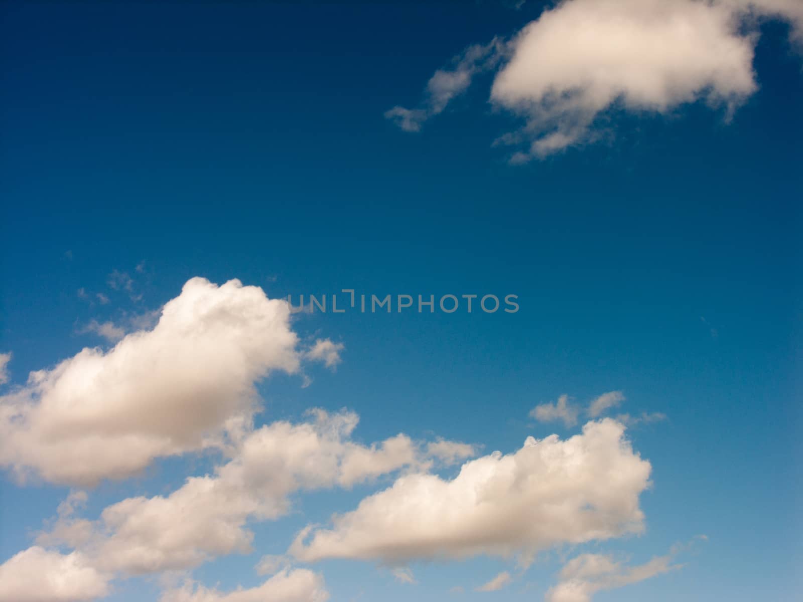 Some white crips clouds hanging over a field on a sunny day