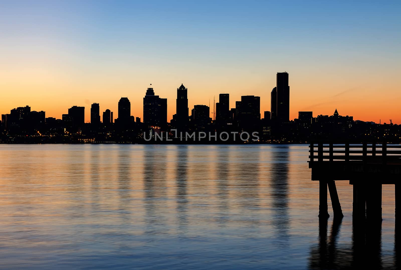 Seattle Washington city skyline silhouette from the pier at Alki Beach during orange glow sunrise 