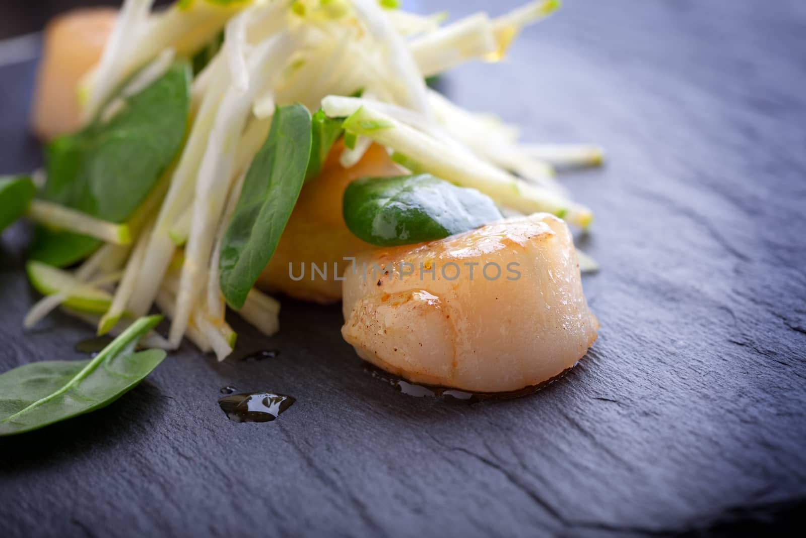 Scallop salad with apple, spinach on a stone plate