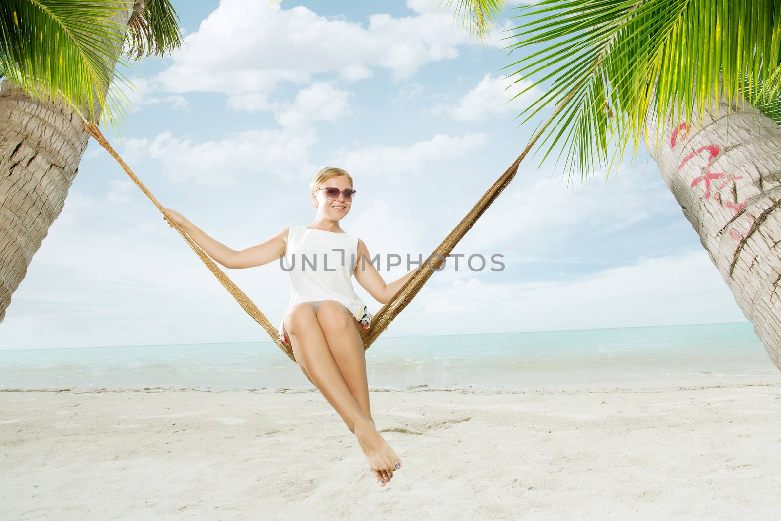 view of nice young lady swinging  in hummock on tropical beach