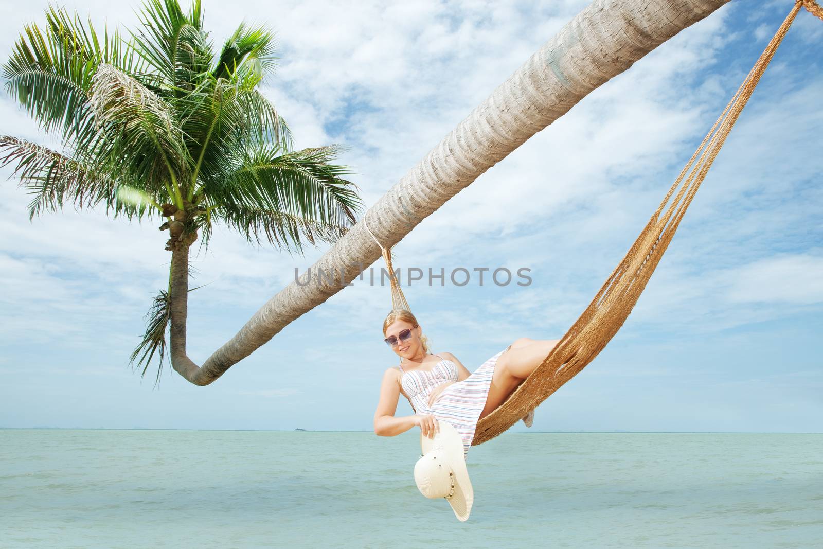 view of nice young lady swinging  in hummock on tropical beach