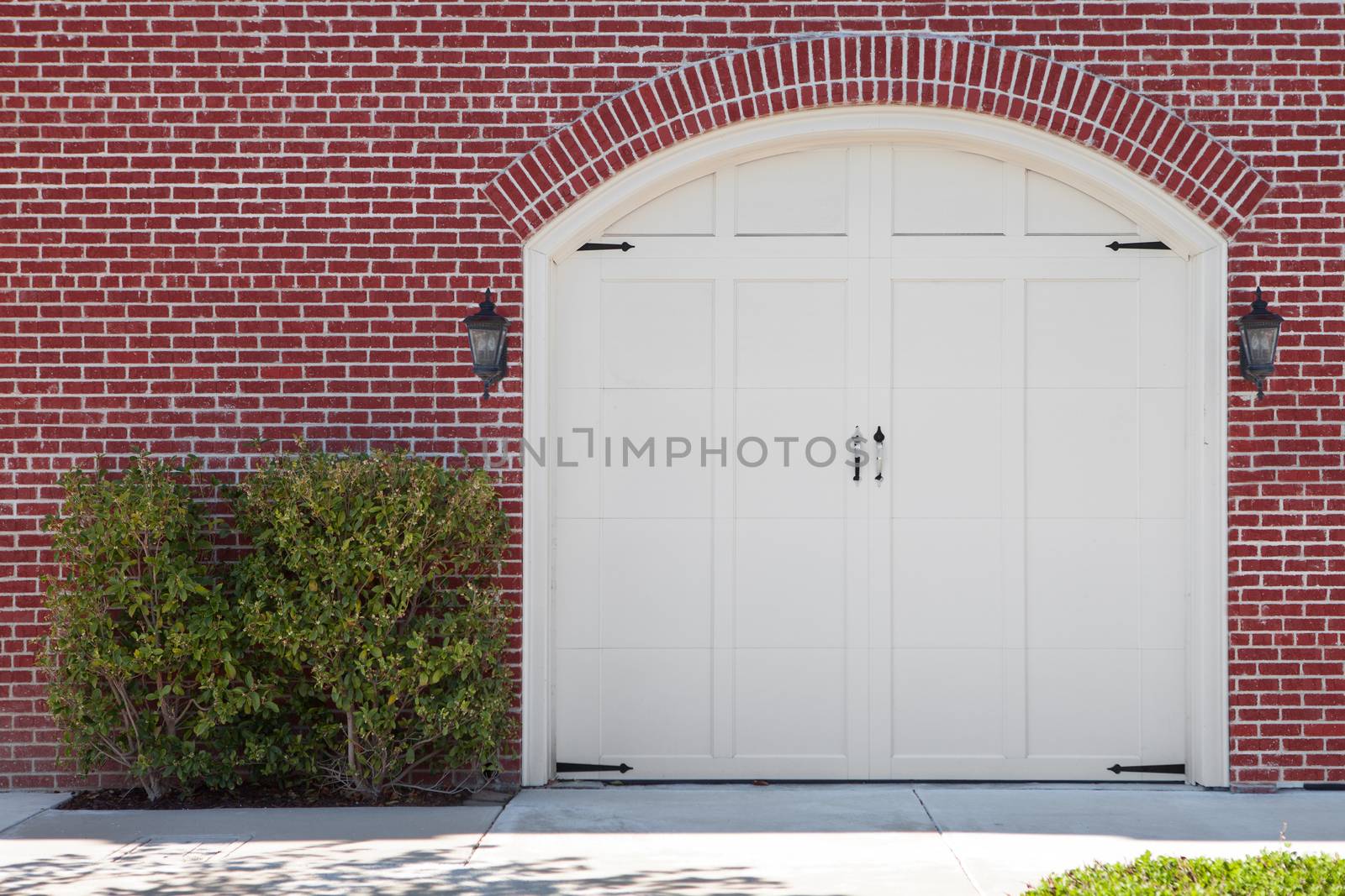 view of white wooden  garage doors and red bricks walls