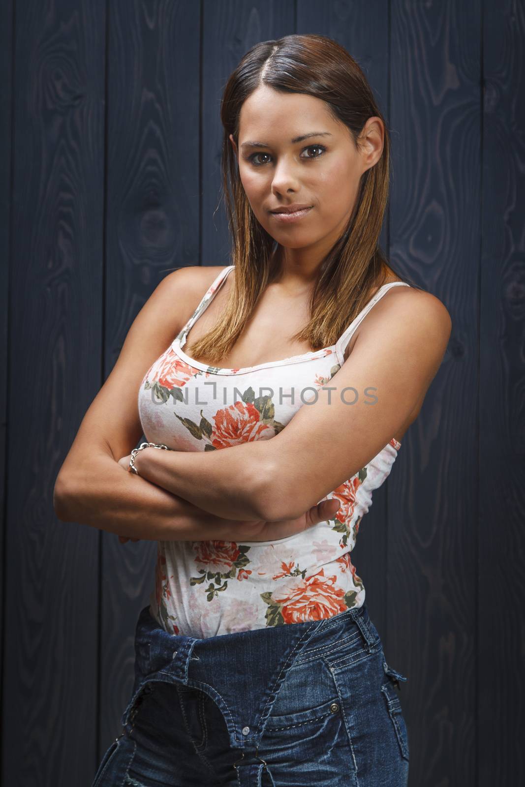 twenty something beautiful girl with floweral pattern tank top and short jean overalls, with arms cross