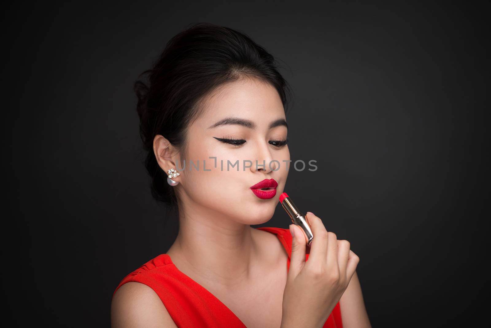 Professional Make-up. Attractive asian model applying red lipsti by makidotvn