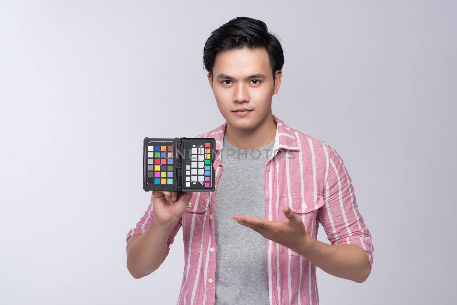 Young asian photographer holding color checker card, while worki by makidotvn